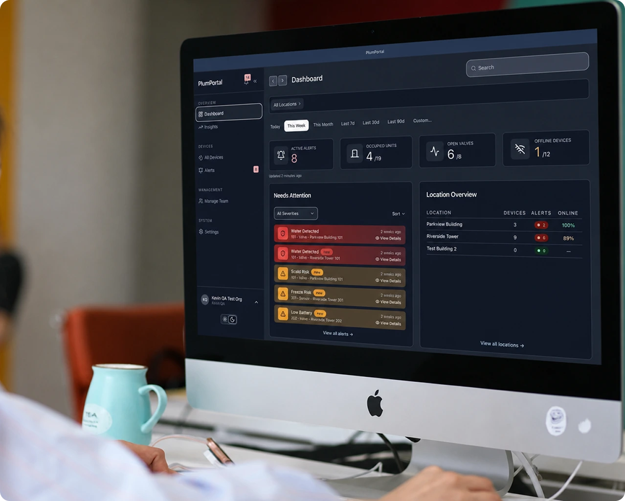 The PlumPortal dashboard open on a desktop computer, showing active alerts, occupied units, open valves and an overview of each location