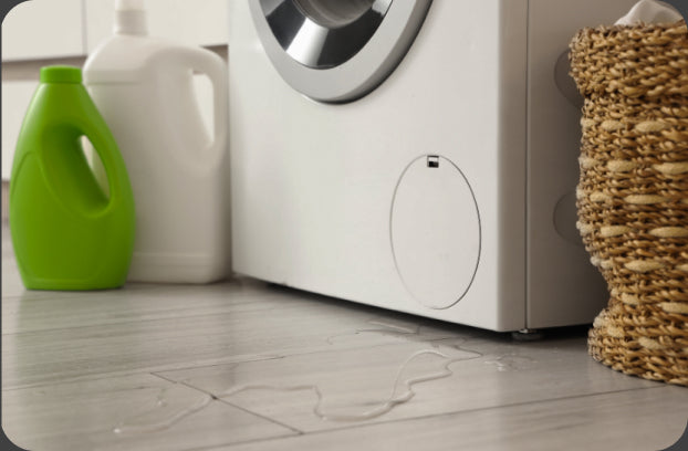 Water spreading across a laundry-room floor in front of a washing machine